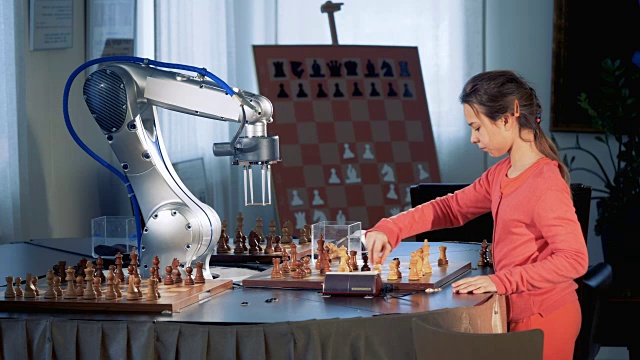 聪明的女学生用机械手臂下棋，象棋机器人。天才儿童的概念。视频素材