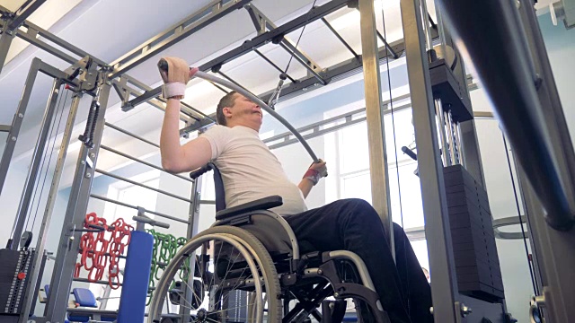 残疾人在轮椅上用举重装置进行训练的过程视频下载
