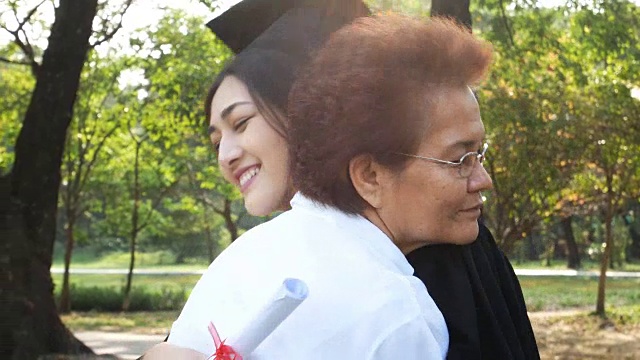 年轻的亚洲女学生戴着毕业帽和毕业礼服在大学，女性与毕业概念。怀着快乐的心情拥抱母亲的女人。视频素材
