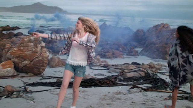 女人拿着烟雾弹在海滩上跳舞视频素材