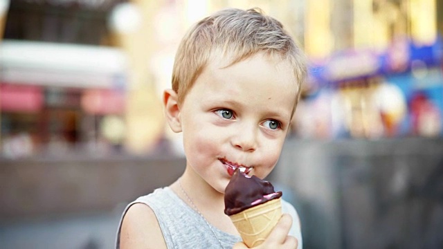 可爱的小男孩在夏天舔着甜筒冰淇淋视频素材