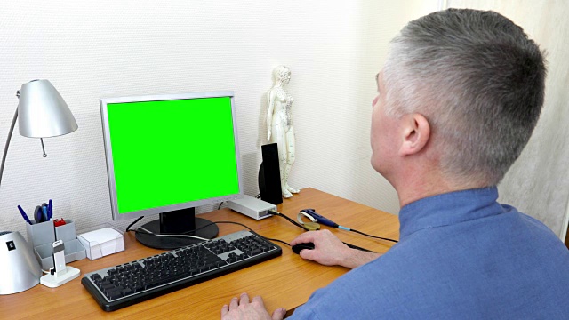医生在一台绿色屏幕的电脑前工作视频下载
