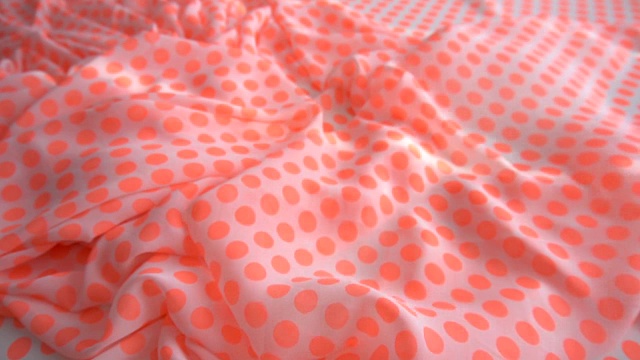 一个背景纹理柔软的橙色点织物织物材料反向移动。视频素材