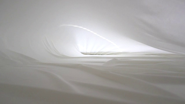 一个背景纹理柔软的白色织物纺织材料波浪移动。视频素材