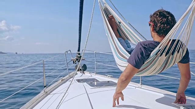4K无忧无虑的人在阳光明媚的帆船上的吊床上放松，实时视频下载