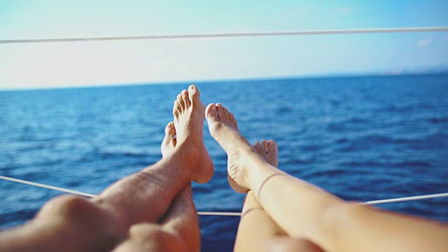 4K个人透视光脚夫妇在阳光明媚的海洋上的帆船上放松，实时视频素材