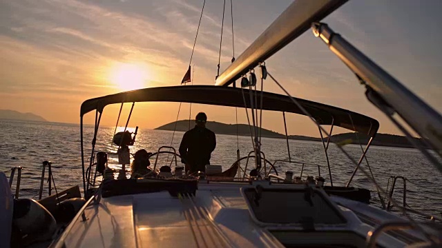 4K剪影的朋友在宁静的日落海洋上的帆船上，实时视频素材