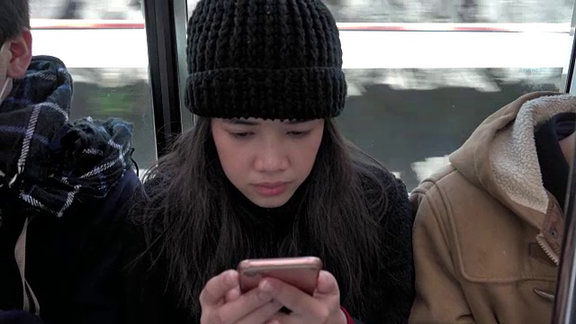 4k:亚洲女性在公共交通工具上坐着时使用手机视频下载