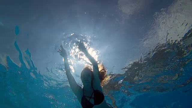 女人在干净的蓝色游泳池游泳与开放的眼睛在充满活力的环境下的背景泡沫视频素材
