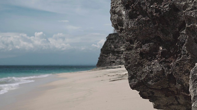 海岸与珊瑚岩石在前景和白色沙滩失去焦点视频下载