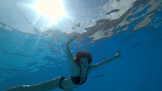 性感的女人睁开眼睛漂浮在慢动作水下充满活力的环境到蓝色的游泳池视频素材