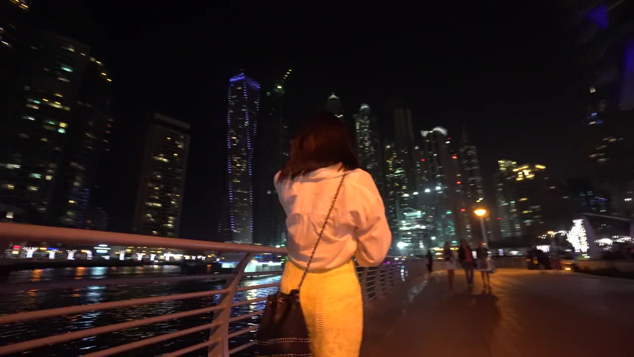 一位女士在迪拜的夜晚走在街上视频素材