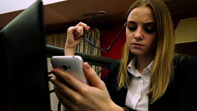 年轻的商务女士看着智能手机拿着眼镜视频素材