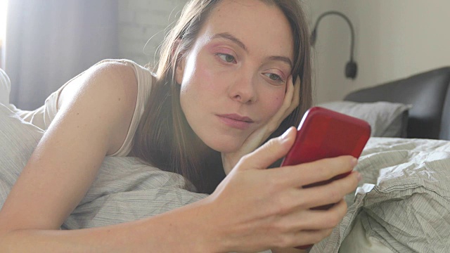 幸福的女人躺在床上微笑发手机短信视频素材