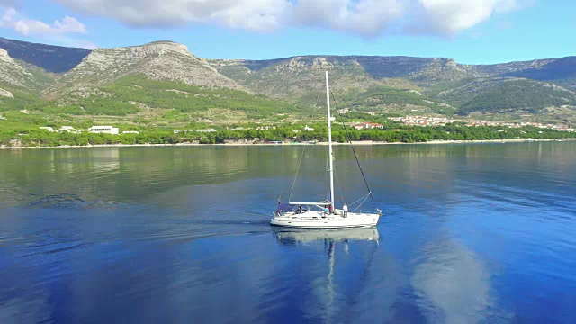4K无人机实时拍摄宁静、阳光明媚的蓝色海洋上的帆船视频下载
