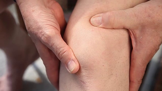 男人按摩酸痛的膝盖特写视频下载