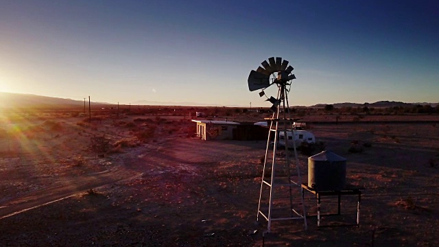 鸟瞰图的风车和拖车在沙漠农场在日落视频下载