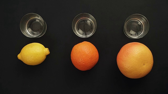 新鲜的橙子、柠檬、柚子被挤进玻璃杯里。定格动画视频素材