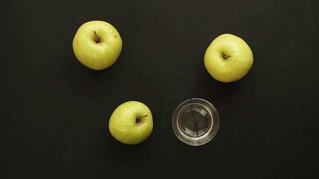 三个新鲜苹果被挤进一个玻璃杯里。定格动画视频素材