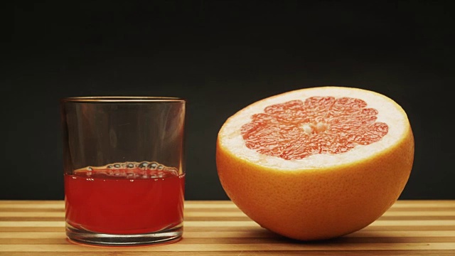 新鲜的橙子葡萄柚被挤进玻璃杯里。定格动画视频素材