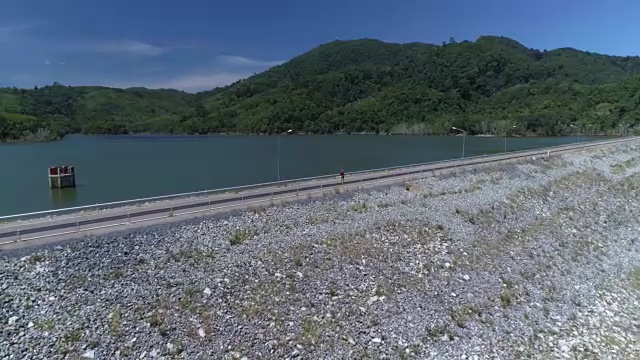 天线:一个孤独的女人走在大坝上的路上。视频素材