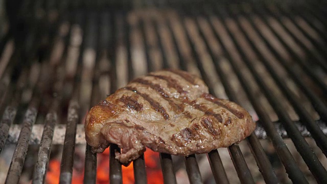烧烤时炸牛排。典型的阿根廷烤肉。在烤架上烧木头和烧红的煤。视频素材