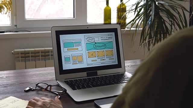 Web开发人员坐在桌子前绘制未来网站的草图。在家办公远程办公视频素材