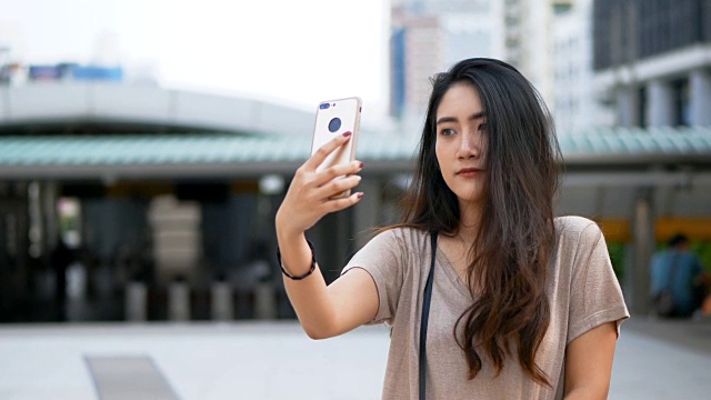 年轻的亚洲女子在用智能手机自拍和视频通话。视频素材