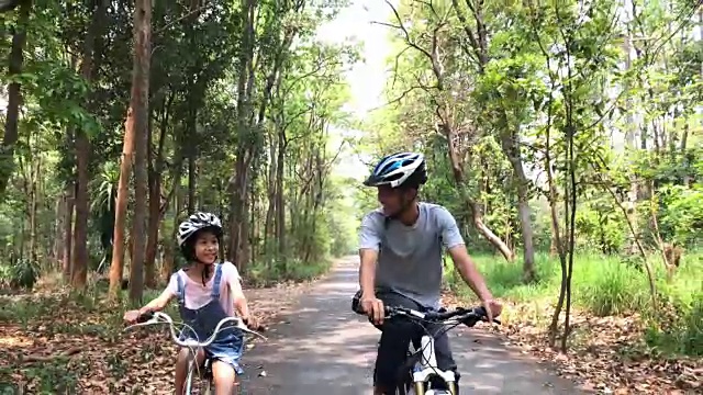 快乐的爸爸和女儿在公园里骑车视频素材