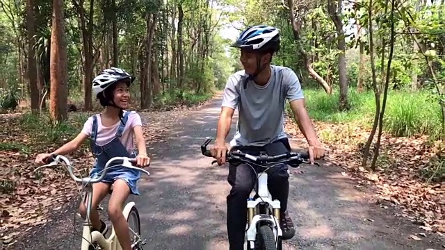 慢镜头快乐的爸爸和女儿在公园里骑自行车视频素材