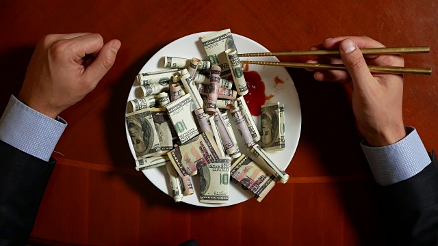一个拿着筷子和美元卷的商人的手。吃美元。4 k。视频下载