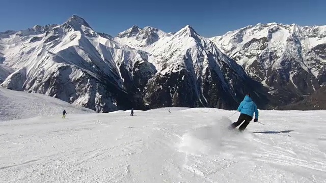 在阳光明媚的冬日，高山滑雪者在滑雪场滑雪视频下载