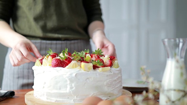 女人用柠檬，酸橙和草莓装饰蛋糕视频素材