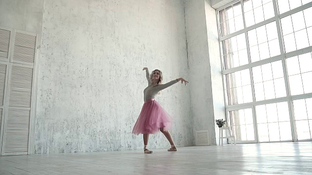 一位年轻的芭蕾舞演员穿着经典的芭蕾舞短裙和尖头鞋踮着脚尖跳舞和旋转。慢动作视频素材