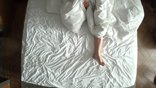 从上往下看，床上是女性的腿，白色床上物品，4k视频素材