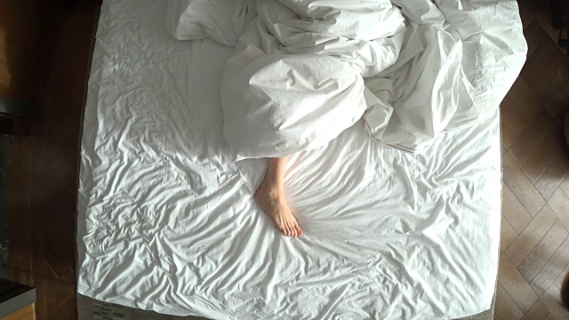 从上往下看，床上是女性的腿，白色床上物品，4k视频素材