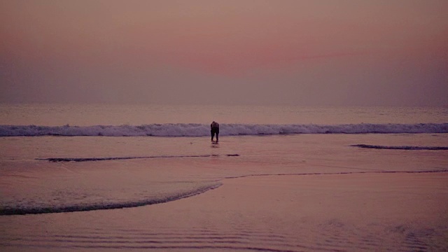 日落时，男人在海滩上洗澡视频素材