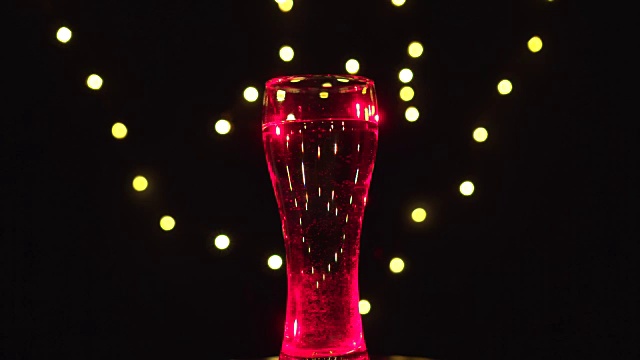 一杯在红光中旋转的水。红色的鸡尾酒。酒吧的概念视频下载