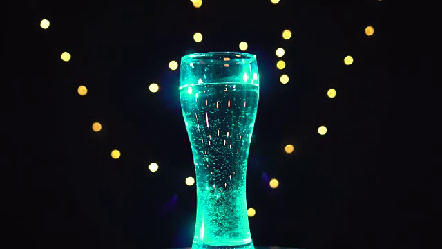 在天蓝色的光线下，一杯水在转动。绿松石杜松子酒鸡尾酒。酒吧的概念视频下载