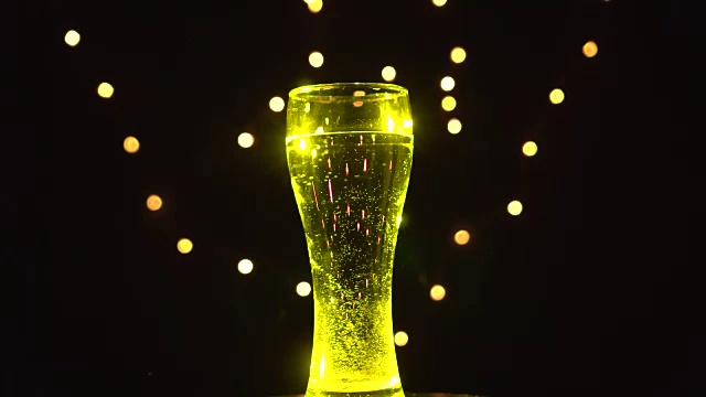 黄色灯光下的一杯水在旋转。黄色鸡尾酒。酒吧的概念视频下载