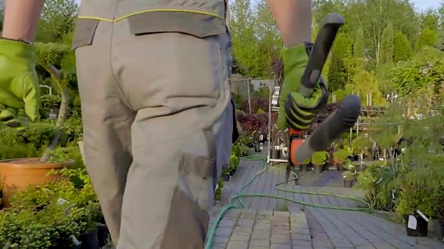 专业园艺师为植物浇水，在花园百货出售。慢动作镜头视频下载
