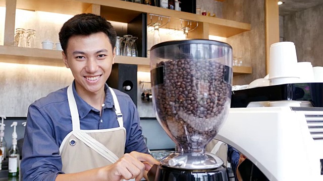 亚洲咖啡师与迷人的微笑工作。视频下载