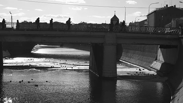 黑色和白色的视频与剪影的人走在堤岸和桥梁的城市河流视频素材