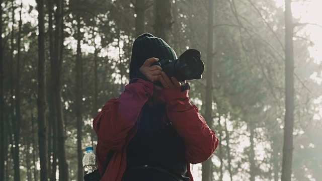一位在森林中活跃的风景摄影师正在用相机拍摄风景视频下载