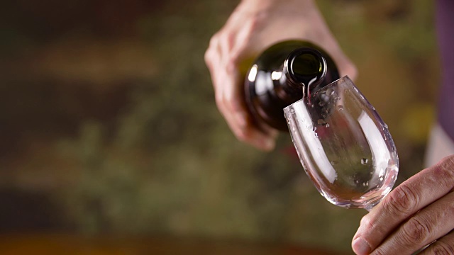男用手将红酒从瓶中倒入玻璃杯中。男人倒红酒视频素材