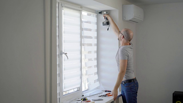 窗户安装师傅是在家里白光房的一个框架上用电动螺丝刀旋转螺丝视频下载
