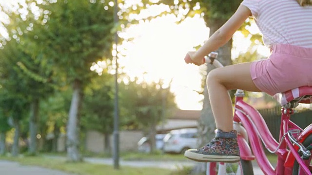小女孩骑着她的自行车，推着踏板，然后把她的脚举到空中视频下载