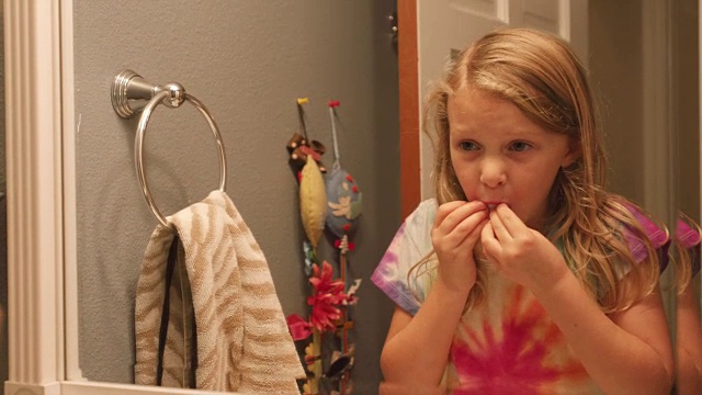 一个小女孩在浴室的水槽边，掉了一颗牙后，把棉花放进嘴里视频素材