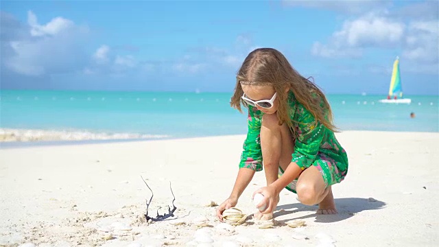 可爱的小女孩在海滩上玩贝壳视频素材
