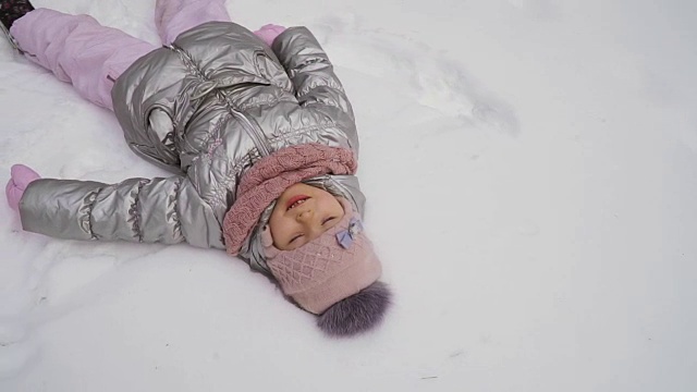 可爱的小女孩躺在雪地上视频下载